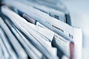 Nahaufnahme eines Stapels Tageszeitungen mit der Überschrift ‚World Business‘ – Symbolbild für Wandel und Umbruch in der Medienbranche